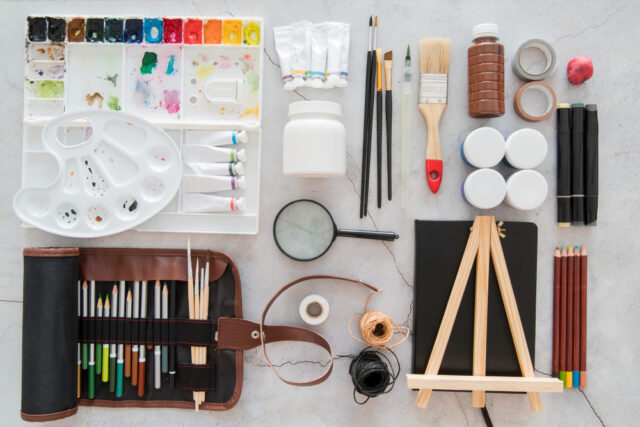 An image of an organized paintbrushes, scissors, pens, rulers, and colored pencils.